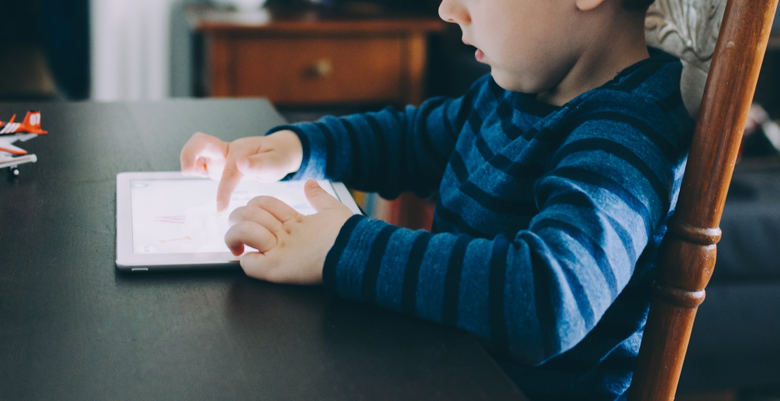 A young child using a tablet at a table at home — the under-13 learners whose personal data COPPA and FERPA protect in edtech products