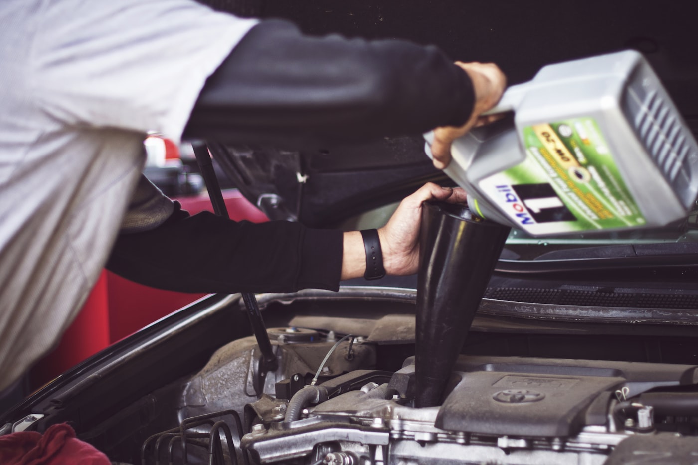 Mechaniker wartet einen Fahrzeugmotor — vorausschauende Wartung und Total Cost of Ownership in Flottenmanagement-Software