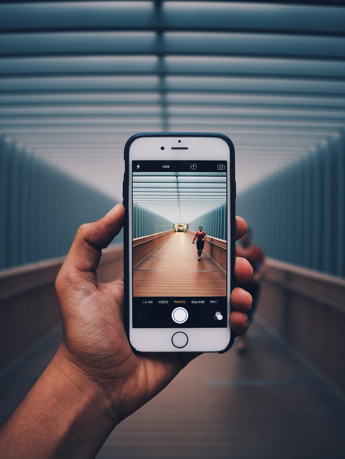 Hand holding an iPhone in a corridor — mobile in everyday context