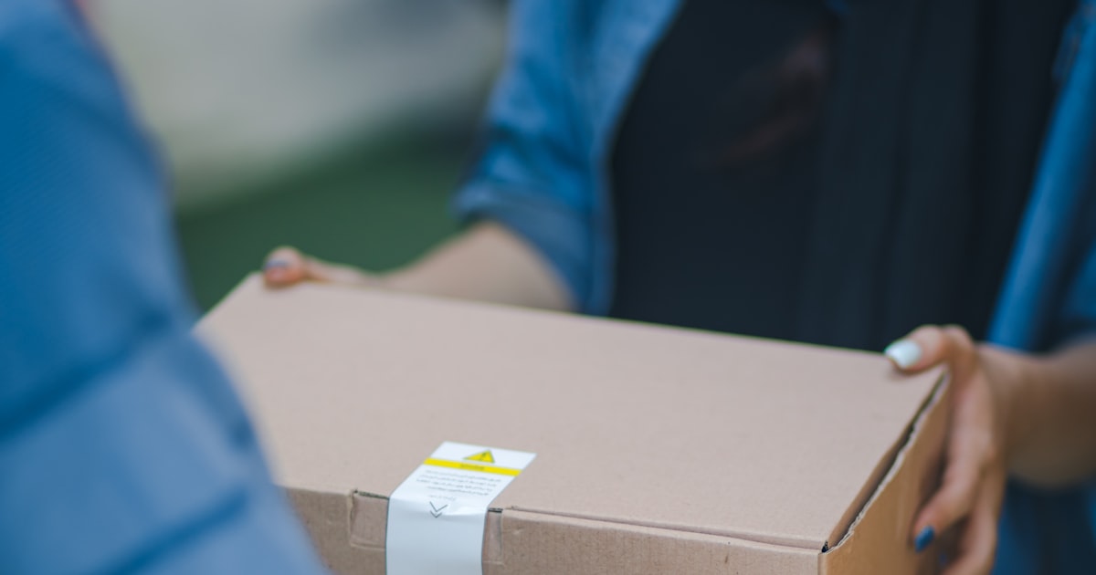 Kurier übergibt ein Paket an einen Kunden — Letzte-Meile-Liefer-App Entwicklung
