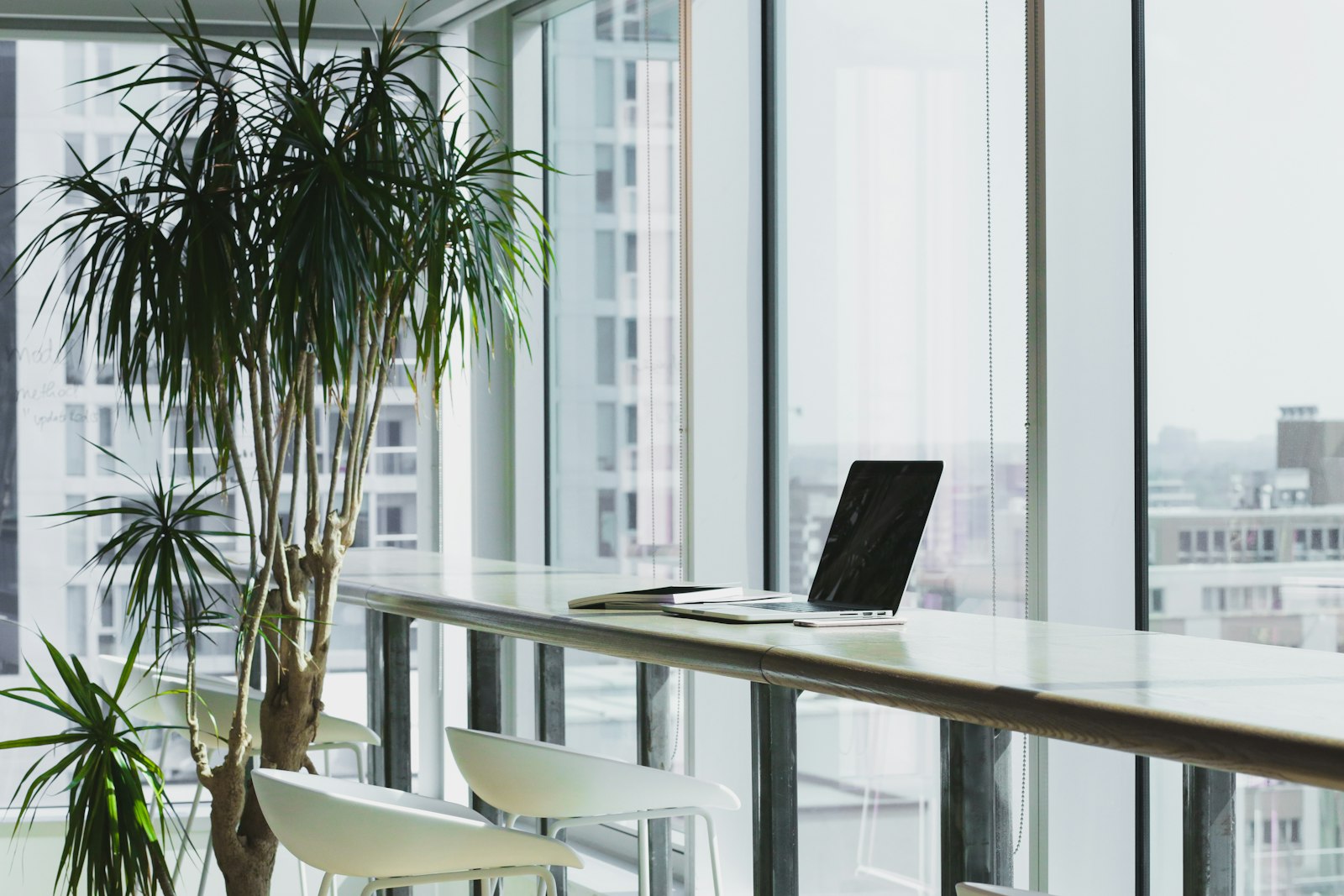 A laptop on a counter by the floor-to-ceiling windows of a modern enterprise office — the IT and RevOps setting where a Salesforce integration is scoped and budgeted
