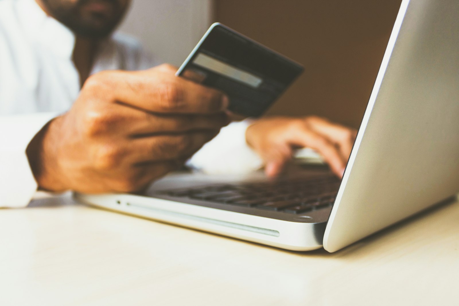 A shopper paying online with a credit card at a laptop — the ecommerce checkout where sales tax is calculated