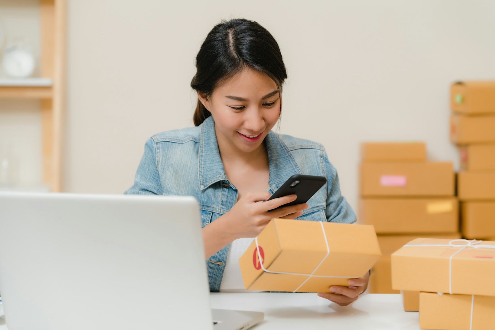 An independent seller packing parcel orders at a laptop — the supply side of a two-sided online marketplace