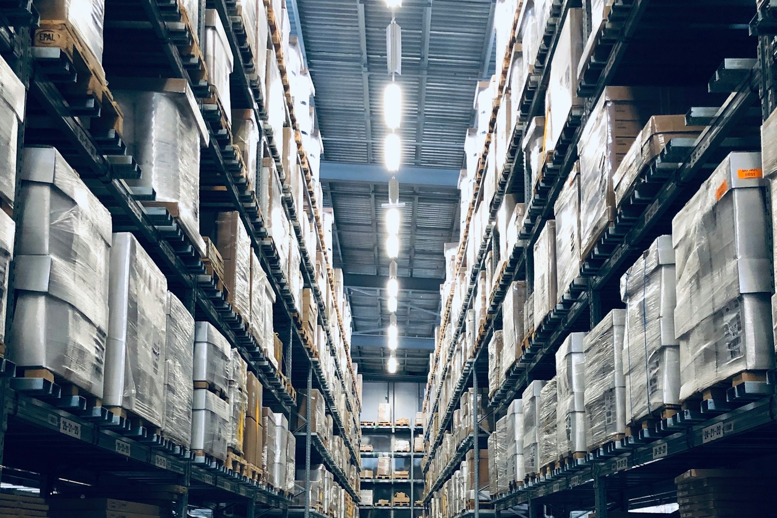 Tall warehouse racking aisle stacked with palletized inventory — warehouse management system development