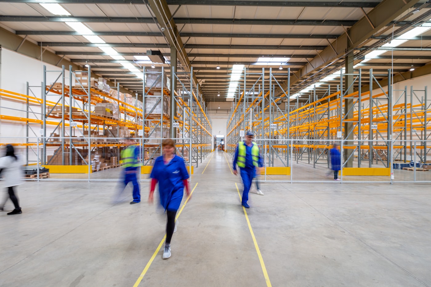 Warehouse staff in high-visibility vests walking through racking aisles during a shift